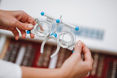 InMedica darbuotojo rankose laikomi optometrijos bandymo akiniai regėjimo patikrai