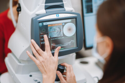 Oftalmologijos specialistas atlieka tinklainės tyrimą naudodamasis skaitmeniniu akių tomografu