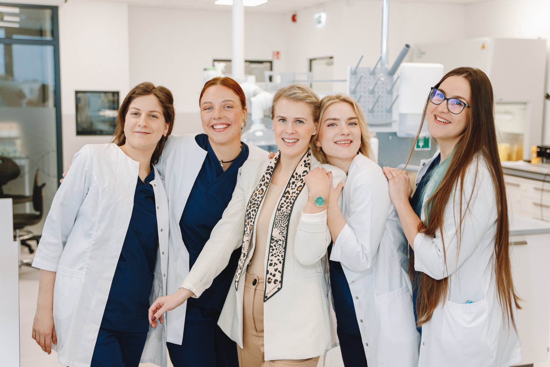 Draugiška InMedica gydytojų komanda klinikoje vilki baltus chalatus ir šypsosi, perteikdamos pasitikėjimą bei profesionalumą